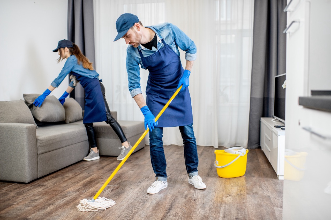Professional cleaning team mopping and tidying living room
